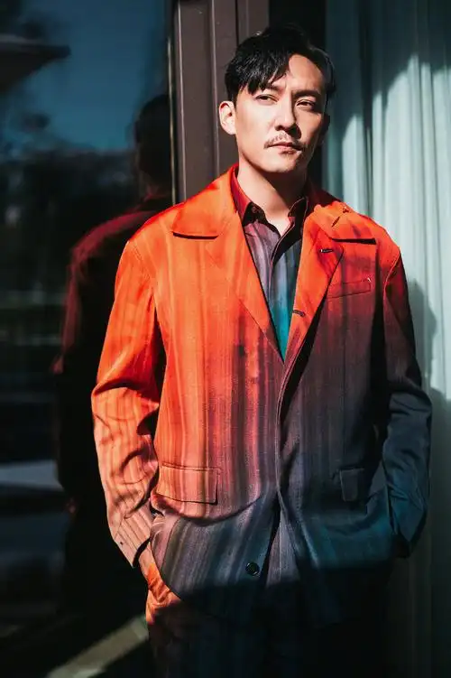 照片中,张震身穿渐变红色西装搭配墨绿色长裤,经典的偏分发型和