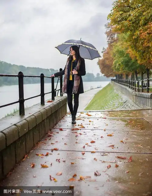 年轻女子撑着伞在秋雨中行走