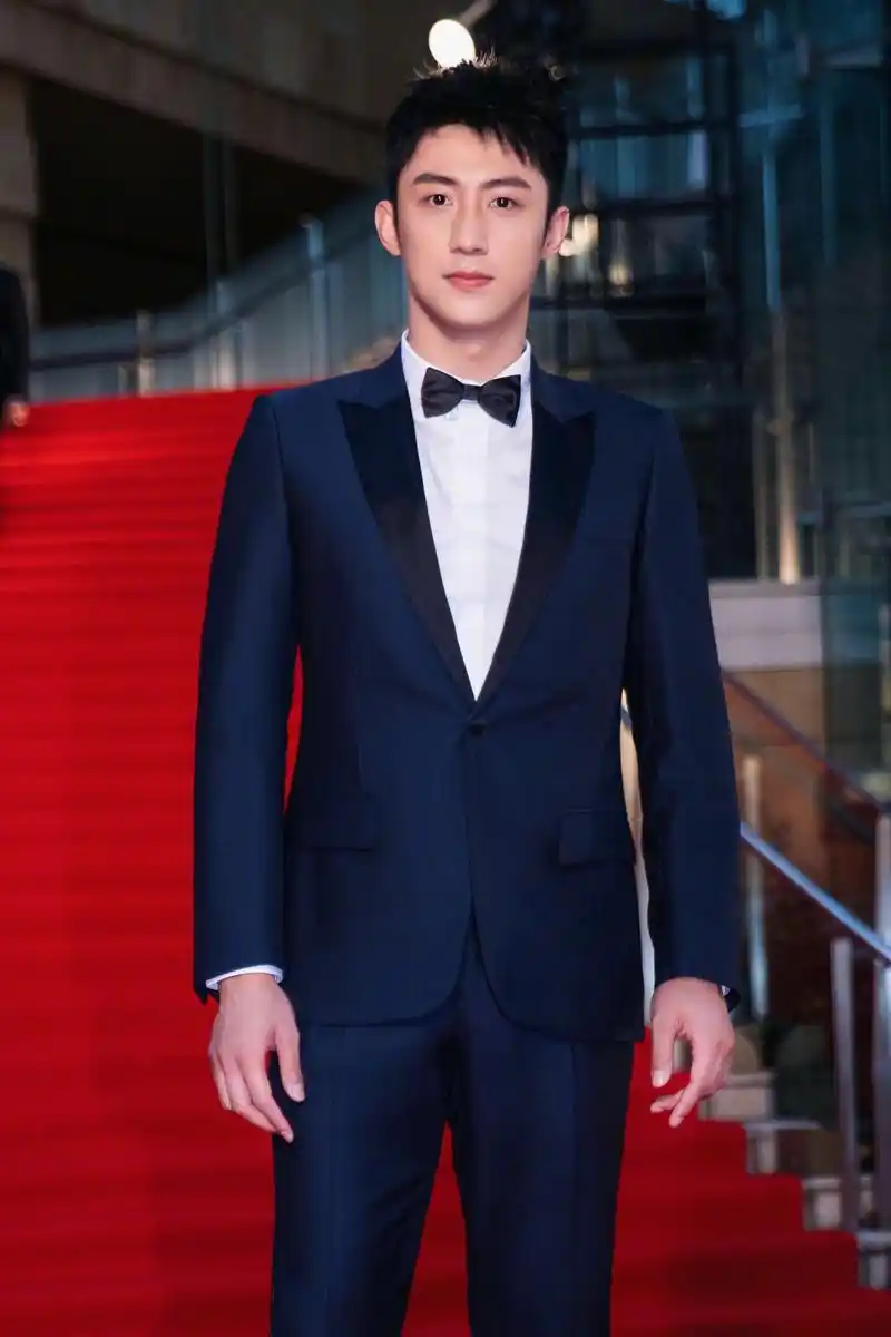黄景瑜亮相东京电影节开幕红毯,身穿深蓝色西装搭配领结,款款走来
