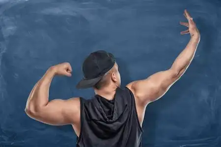 健康运动员弯曲和拉伸手臂肌肉的深蓝色背景上的背影肖像照片