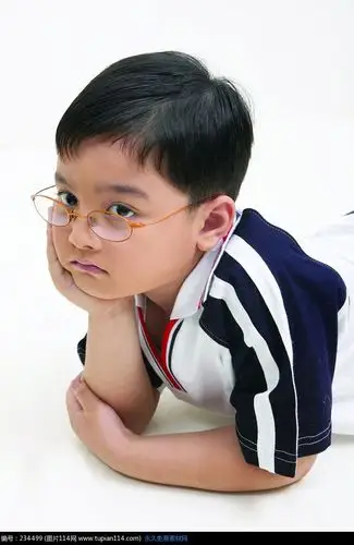 戴着眼镜靠在桌上沉思的男孩