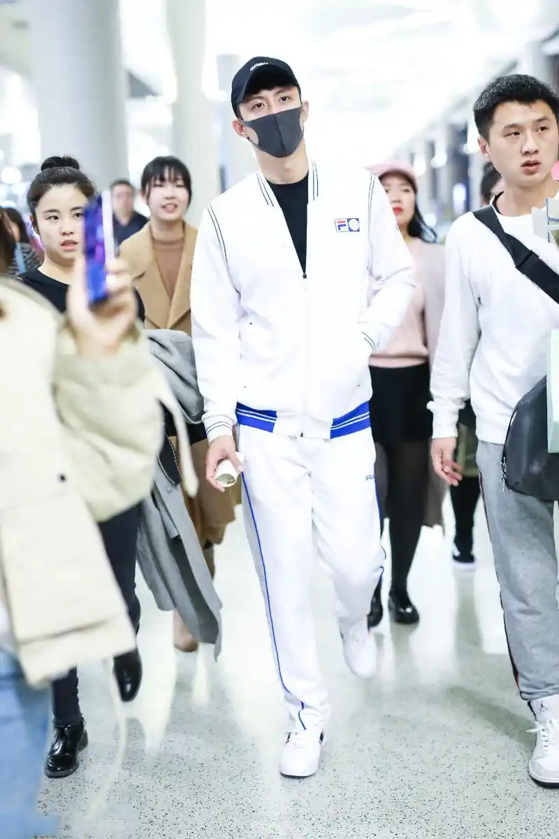 黄景瑜穿白色运动装现身机场,戴黑色棒球帽和口罩遮面