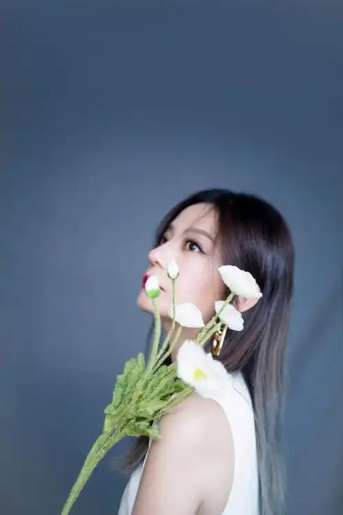 照片中,赵薇披着秀发,身穿无袖白色连衣裙搭配红唇,造型明艳大气,举手