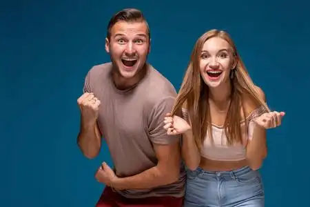 喜出望外的女人和男人都胜利地举起拳头, 成功了交易, 在蓝色的背景下