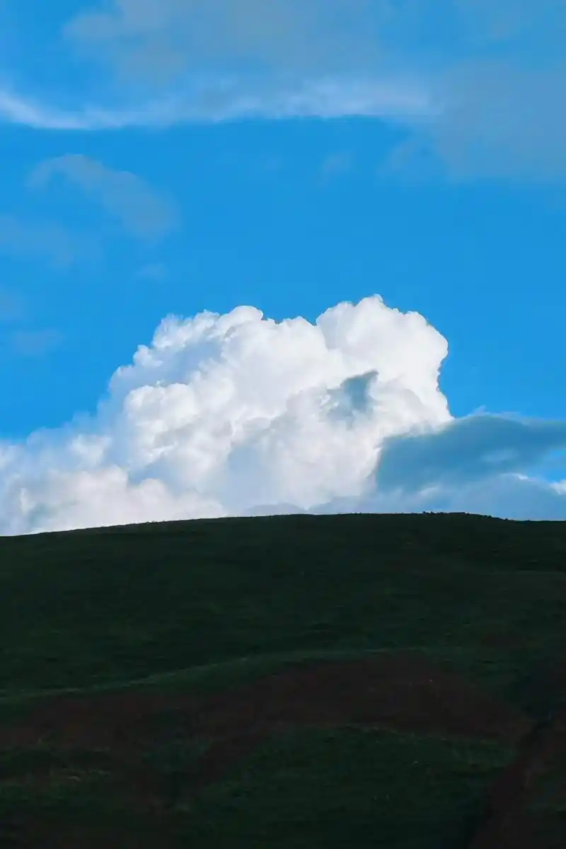 云朵轻盈绘天际,白得纯净如诗行,蓝天为布,绘就一幅梦幻长卷.山丘轻拥