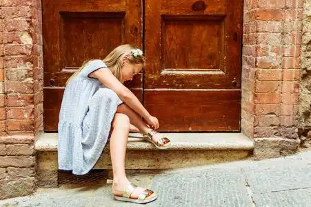 黑色爱瑞安一个可爱的小女孩,穿着黑色和白色的长裙和金色凉鞋的户外