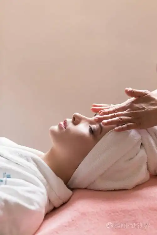 女人闭着眼睛躺着, 在水疗中心做脸部或头部按摩