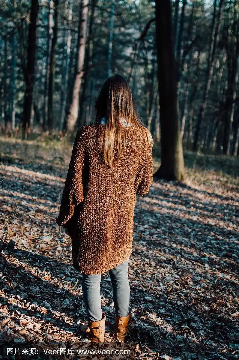 一个黑发女人在树林里散步的背影