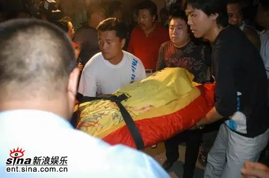 图文:高秀敏遗体被家人用黄色缎面包裹抬出家门