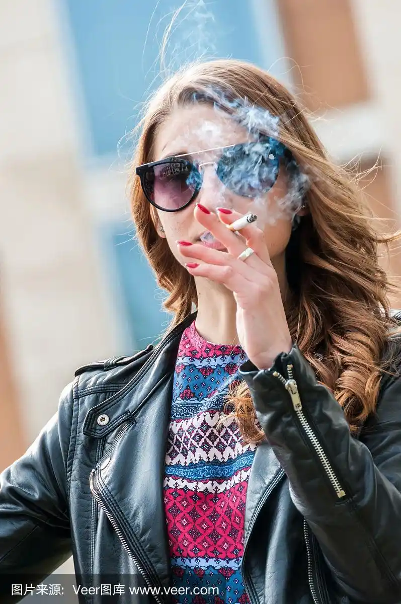 美丽的女性吸烟与烟雾在面前