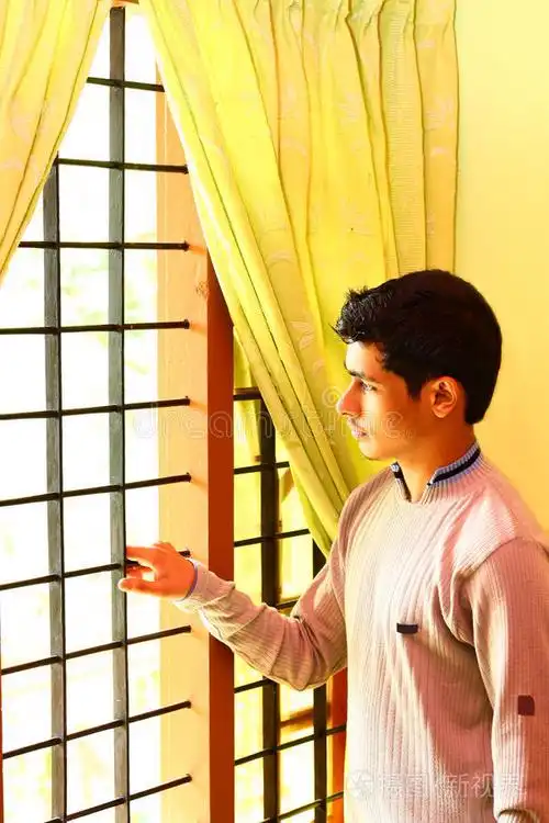 孤独的印度男孩透过窗户向外看