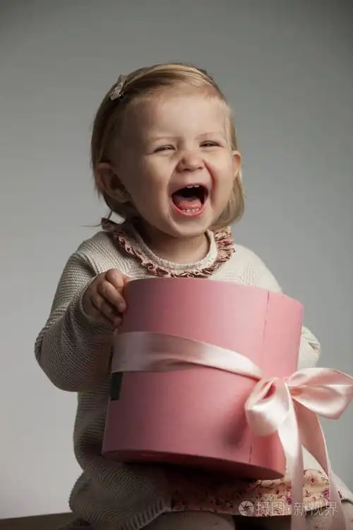 小女孩拿着粉红色的盒子笑