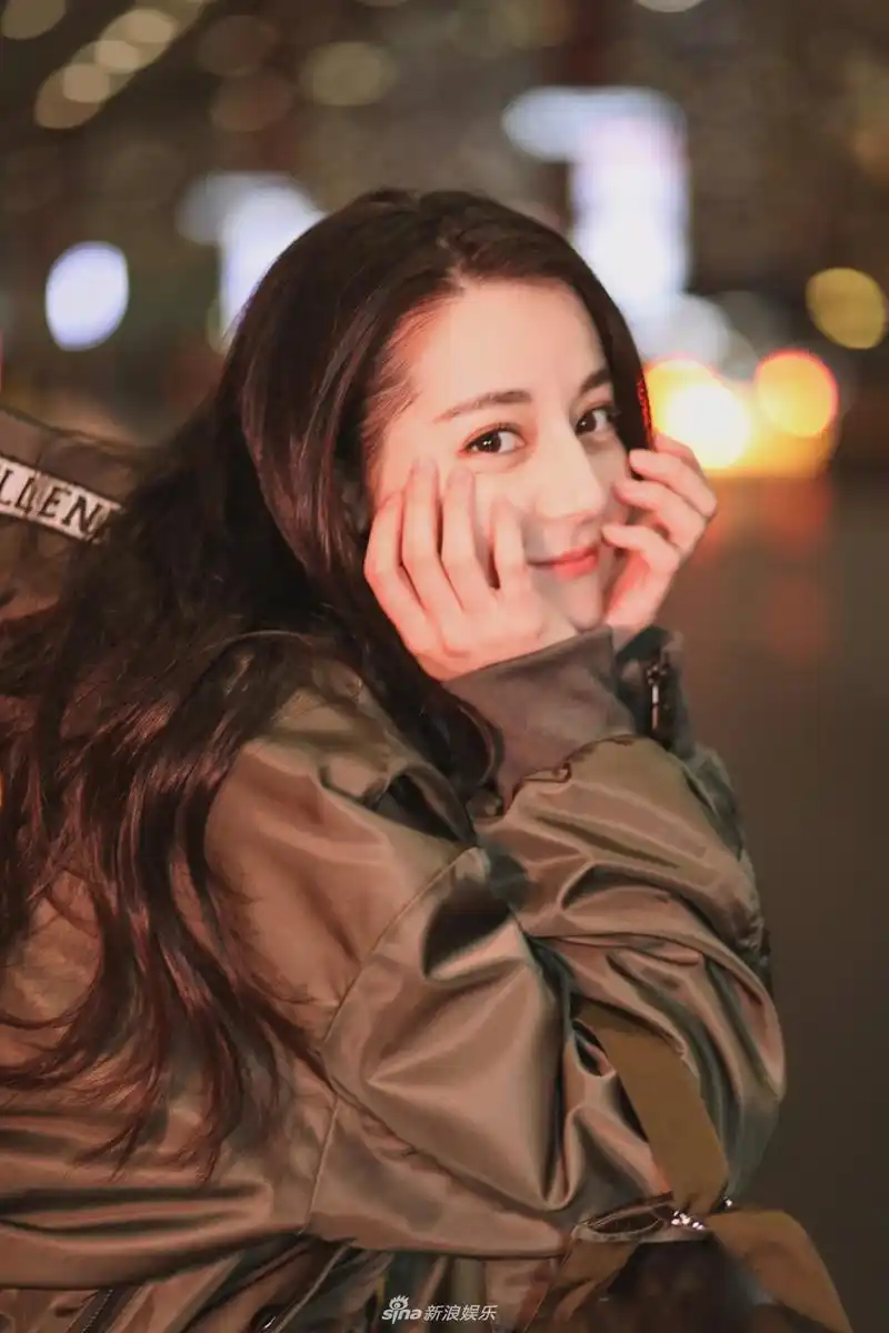 迪丽热巴靠栏杆托腮回眸高举双手比v萌态十足