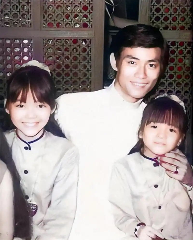 图为香港影星郑少秋抱着梅艳芳两姐妹的合照.