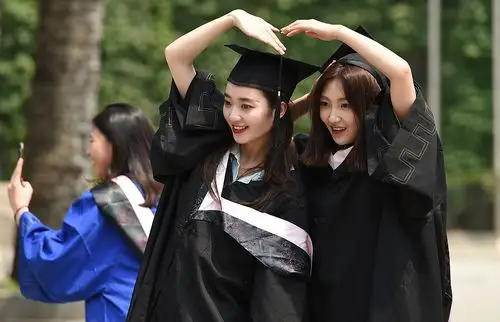 毕业生身着学士服在校园外与亲友拍摄合影.
