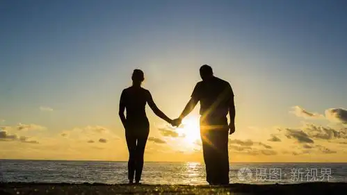 夏天日落时, 一对夫妇的剪影在沙滩上一起散步的全景