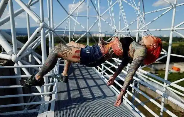 志愿者凯特琳为了测试人体疼痛承受力的极限,将自己全身穿孔吊环悬挂