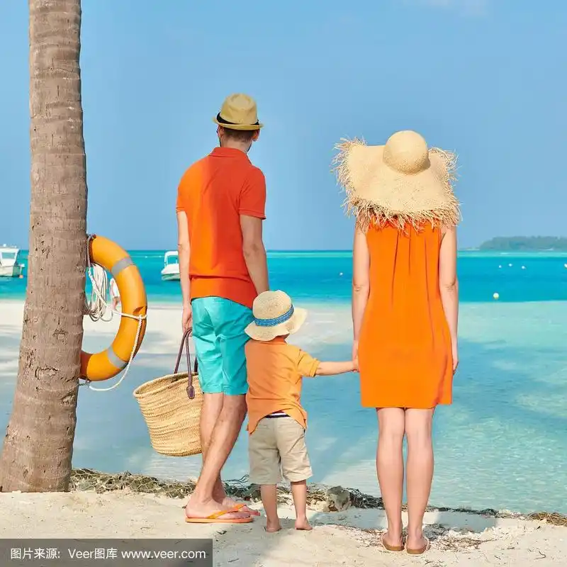 一家三口在沙滩上的棕榈树下