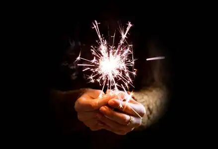 在晚上的烟火女孩的手拿着一个烟火.在黑暗中.晚上.隔离在照片