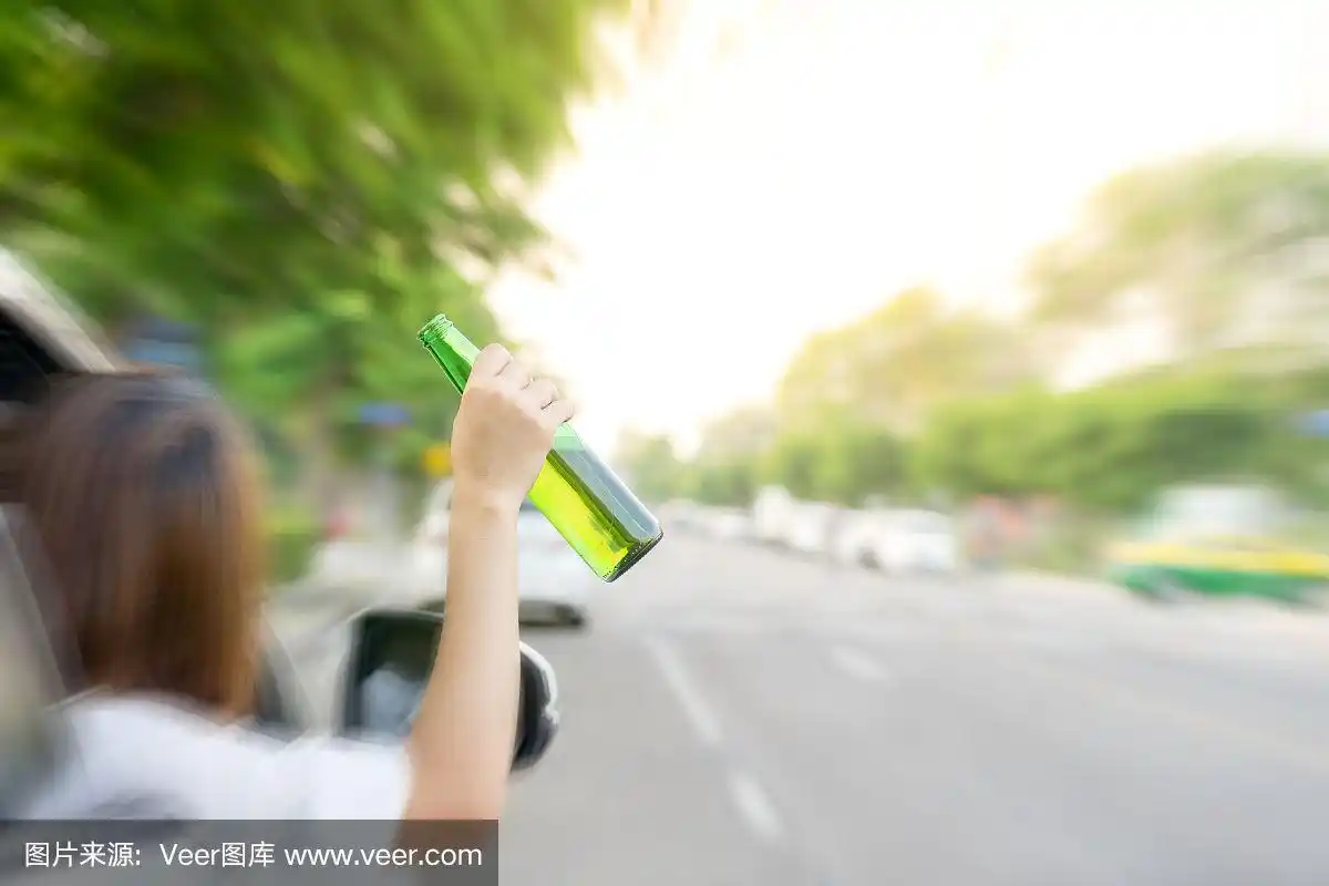 一个喝醉了的女人在车外开车,手里拿着啤酒瓶.