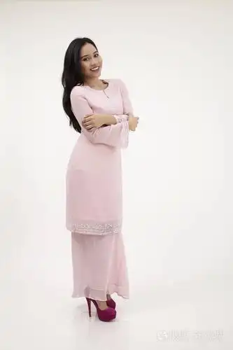 马来西亚妇女穿着粉红色的 baju kurung 传统的衣服摆在工作室