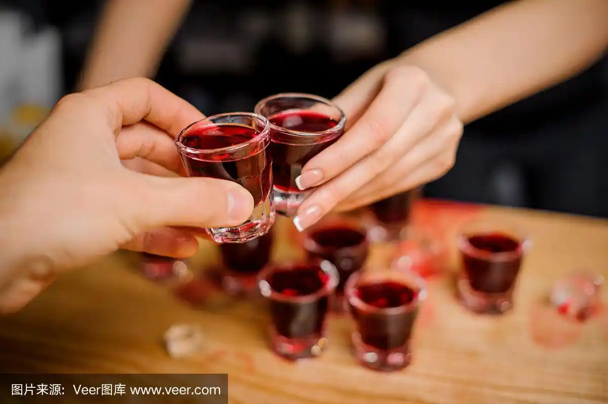 酒吧女招待与客人碰杯用红色的酒精