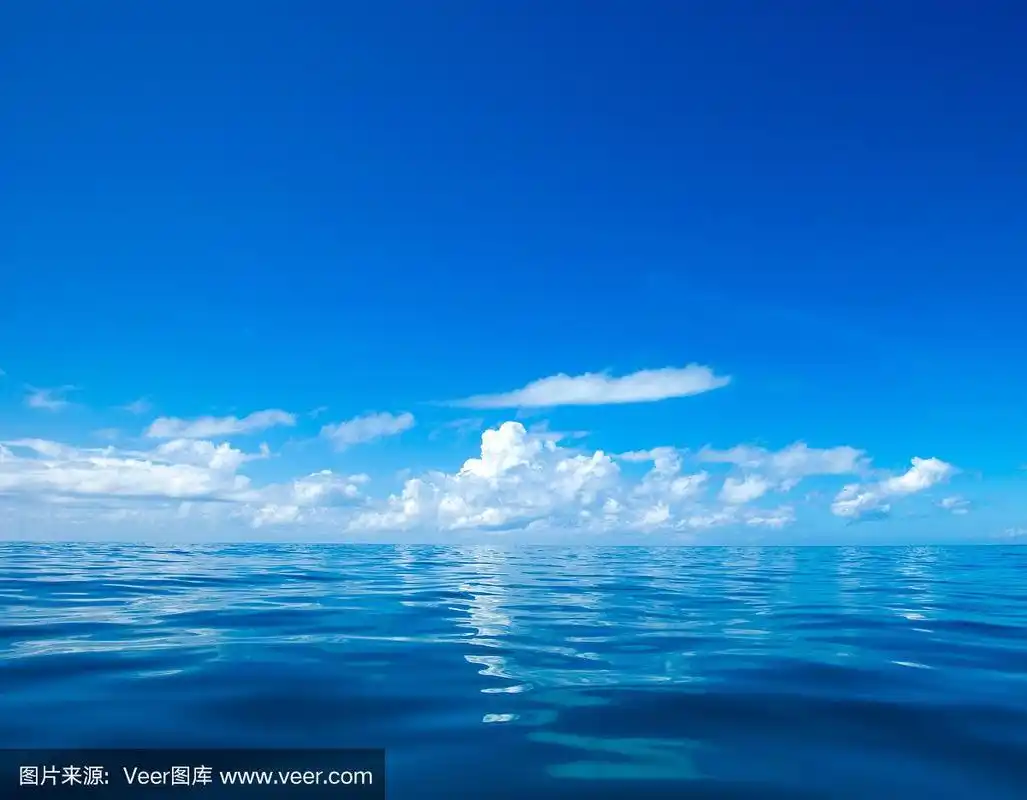 平静的海面上,蓝天上的云朵反射着阳光