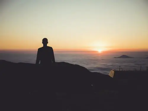 日落时分,一个身穿白色礼服的女人站在海滩边