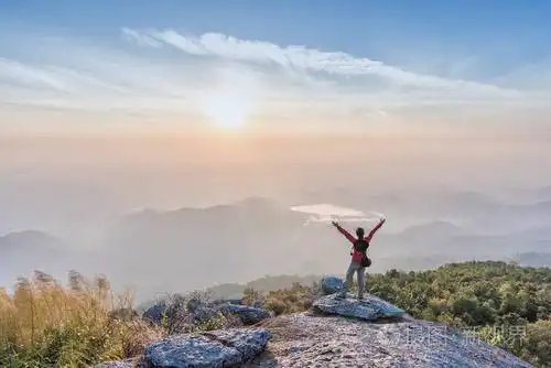 成功的女人在悬崖上传播徒手攀爬和欣赏日出的景色