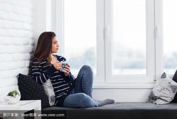 年轻女孩坐在窗边喝着咖啡,放松着.