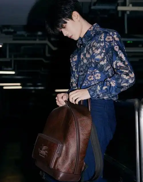 任嘉伦米兰时装周机场出发图曝光,蓝色花衬衫深棕双肩包复古时尚