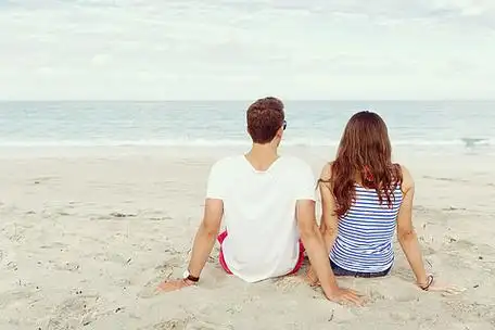 浪漫的年轻情侣坐在沙滩上浪漫的年轻情侣坐在海边看着大海