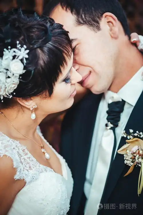 照片 接吻的结婚礼服的年轻夫妇.新娘控股束鲜花.jpg