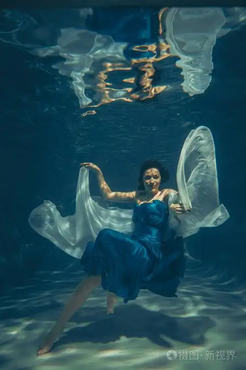 一个穿着蓝色晚礼服的自由潜水员独自在水下游泳