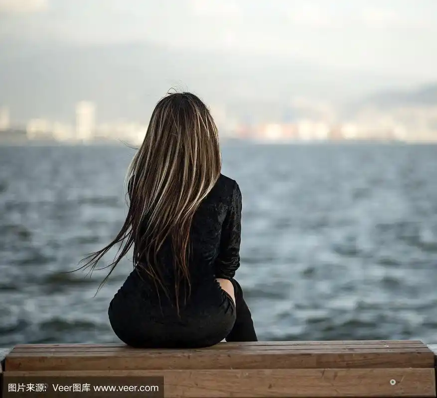 一个有着长长的直发的漂亮女孩坐在海边