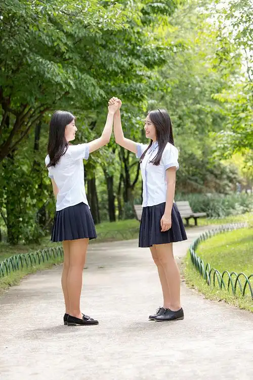 两名女学生在公园面对面鼓掌的照片图片