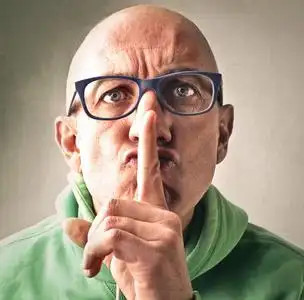 年轻男子表现出闭嘴和沉默的手势,就像在孤立的粉红色背景上用拉链