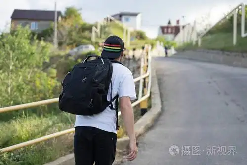 背包的时尚年轻男人独自行走在山路上