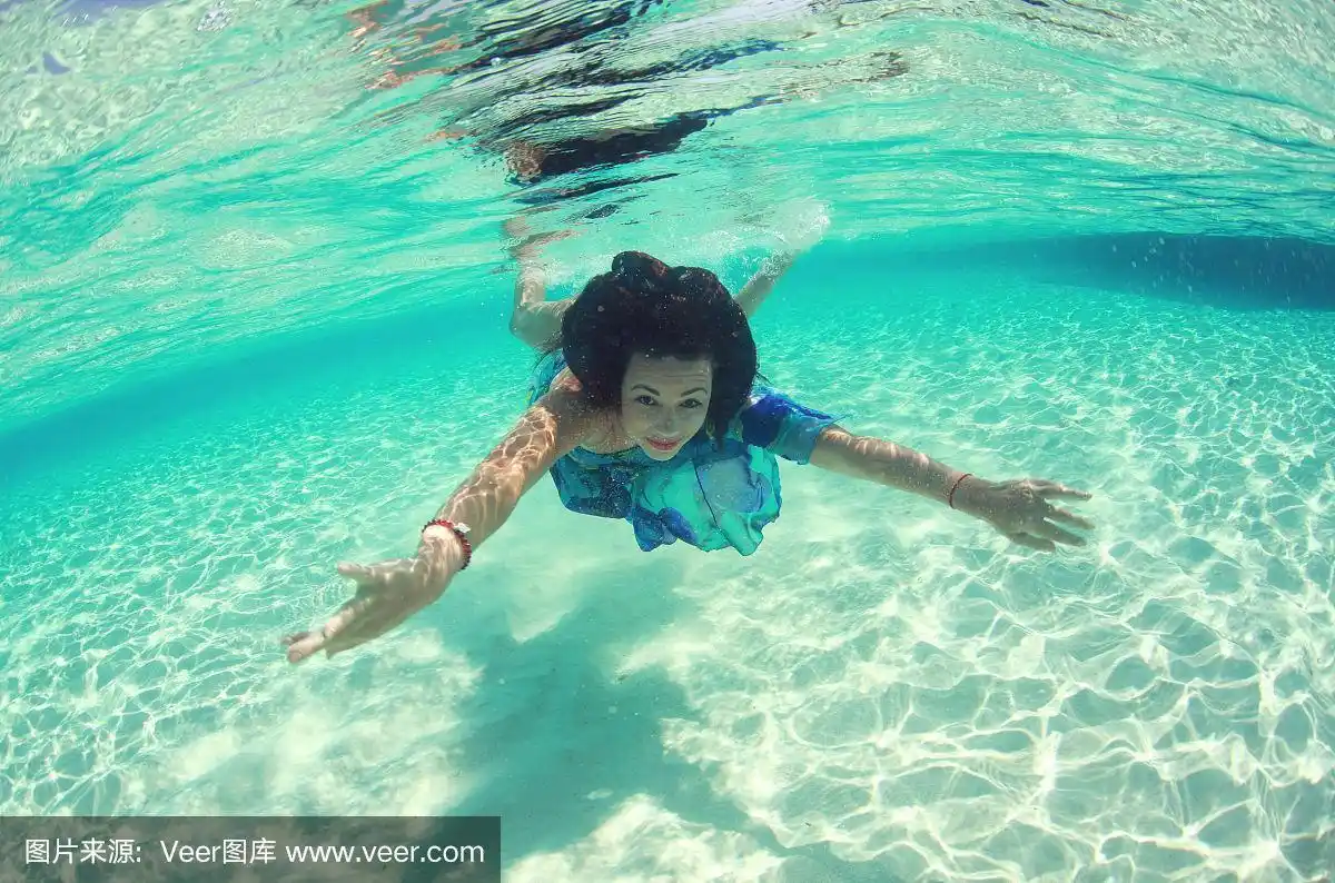 可爱的女人穿着裙子在海里游泳