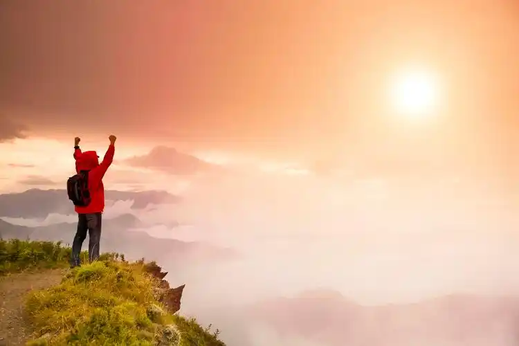 站在山顶看日出的背包的年轻人励志挑战极限突破自我