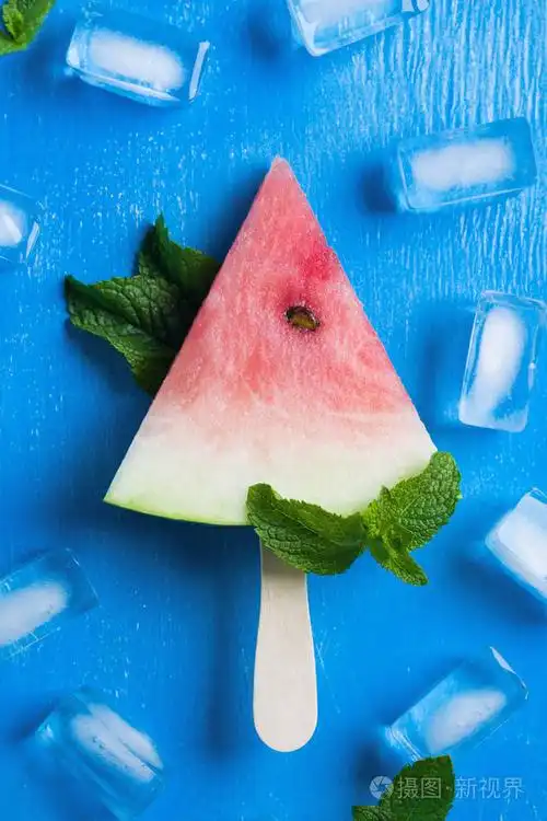 西瓜冰棒与轻木棒, 薄荷叶, 冰块在蓝色的木质背景.垂直方向, 平躺,
