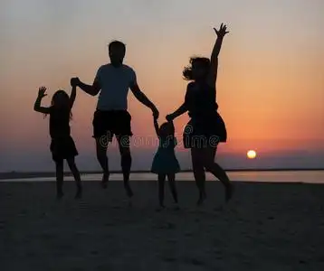 幸福一家人合影留念幸福美丽的一家人在夕阳下跳在沙滩上照片