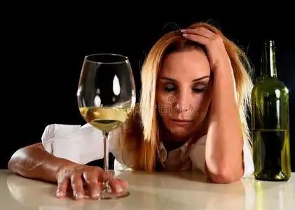 醉醺醺的金发女人独自在醉醺醺的醉醺醺地喝着白酒杯,宿醉照片