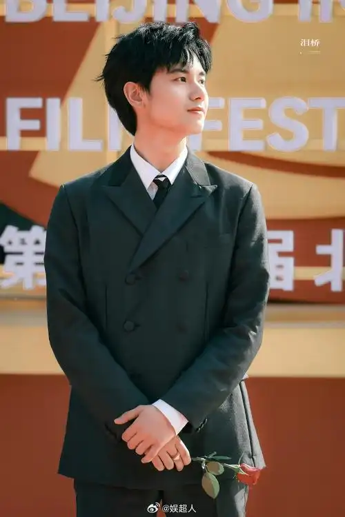 胡先煦穿着黑西服拿着一枝红玫瑰走地毯,还对粉丝比心这哪里是在走