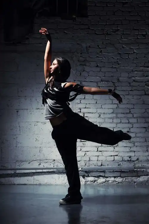 灰色背景前穿着休闲服装跳舞的女孩