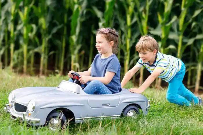 男孩驾驶汽车与里面的小女孩.笑,笑的孩子.家庭,童年,生活方式的概念