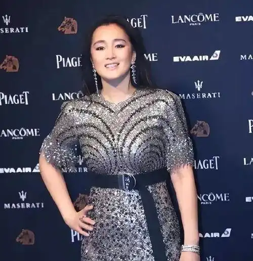 照片中,巩俐发福明显,身穿白色连衣裙,皮肤偏黄,与她年轻时的风采形成