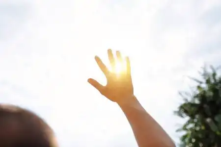 伸向太阳一只手伸向天空, 遮住太阳, 太阳的光芒穿过手, 特写照片