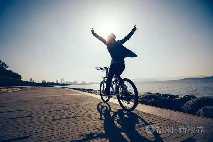 在日出海岸骑自行车的快乐骑车的剪影