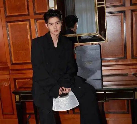 时装秀上,刘昊然身穿西装外套和西装裤,手上拎着一个白色的包包.